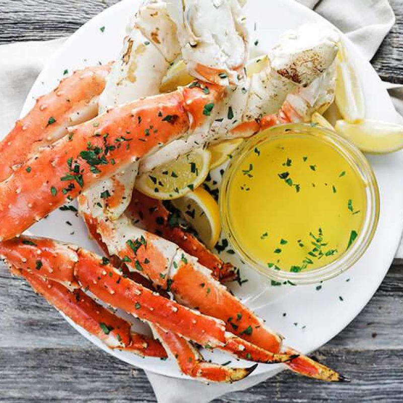 cooked king crab legs with melted butter and lemon wedges